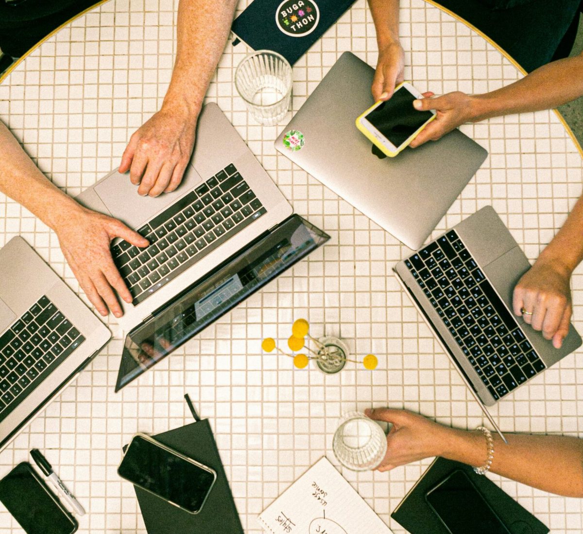 Top view of a team collaborating with laptops, phones, and notes in a modern office.